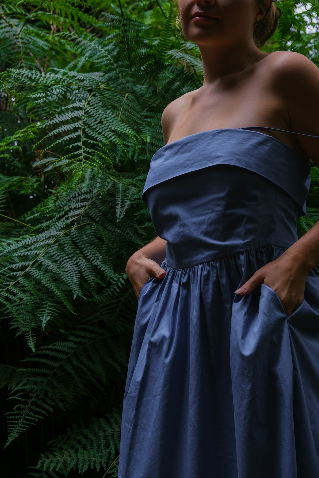 In nature's embrace, serenity intertwines with the elegance of human form by Clothing Brands a woman in a blue dress standing in a forest