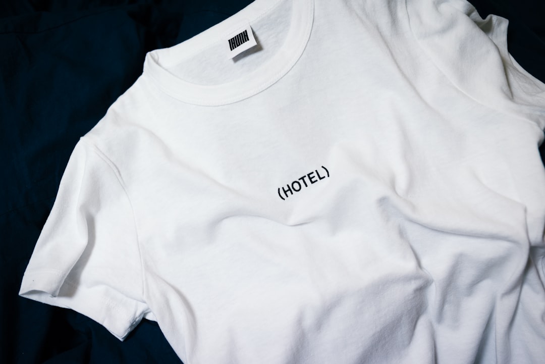 (HOTEL) by Clothing Brands white hotel-printed crew-neck shirt on black surface