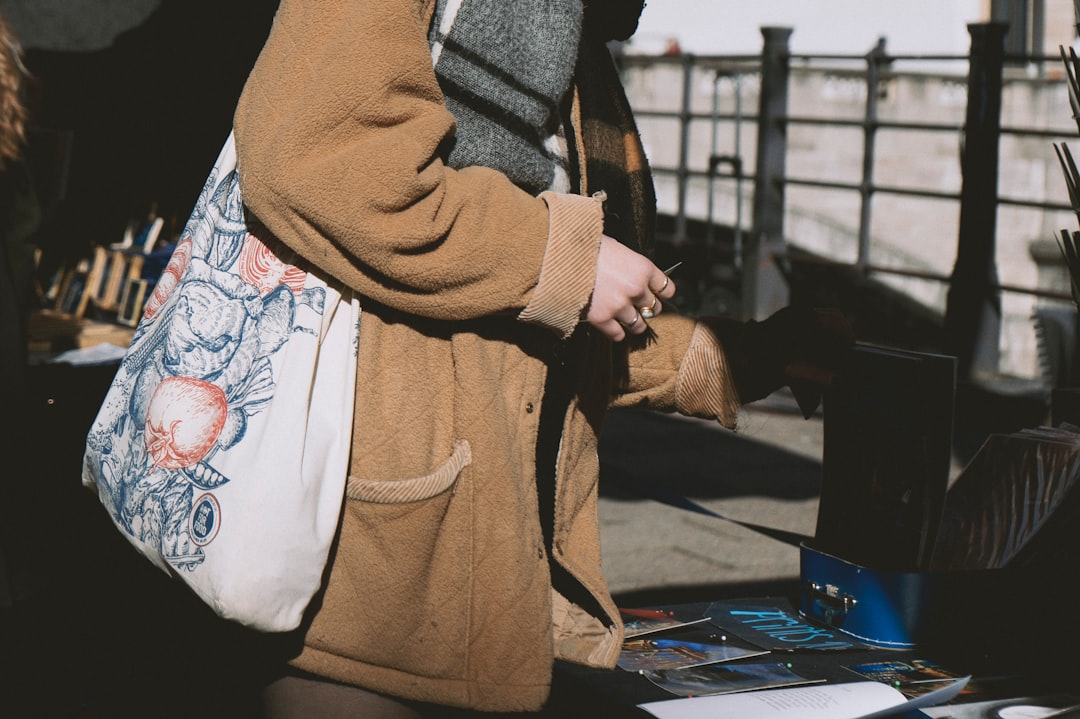 Person browsing a stall with a patterned tote bag.